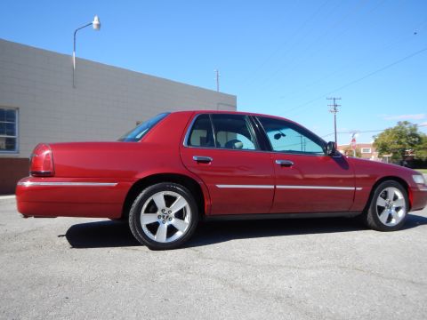 2002 Mercury Grand Marquis - Side view of a red 2002 Mercury Grand Marquis sedan with chrome trim and five-spoke wheels.