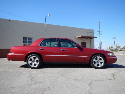 2002 Mercury Grand Marquis - A red 2002 Mercury Grand Marquis is shown from the side, parked in front of a commercial building.