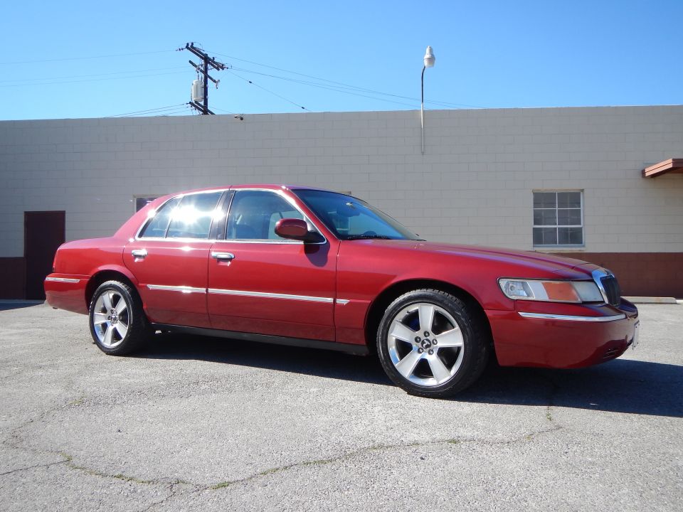 Red 2002 Mercury Grand Marquis sedan with chrome trim and five-spoke wheels