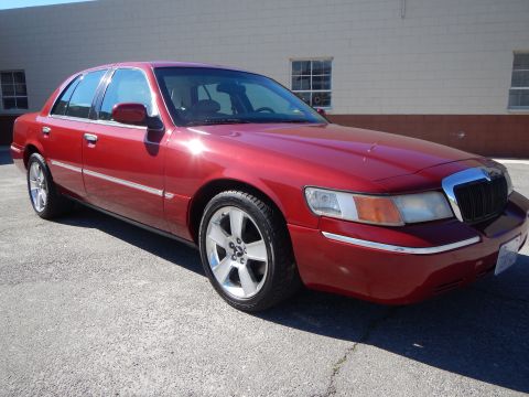 2002 Mercury Grand Marquis - This red 2002 Mercury Grand Marquis is shown from a three-quarter front angle, highlighting its custom wheels and chrome accents.