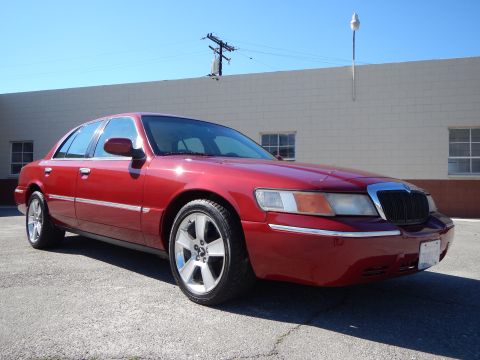 2002 Mercury Grand Marquis - A red 2002 Mercury Grand Marquis is shown from the front three-quarter angle against a building.