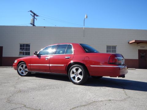 2002 Mercury Grand Marquis - Red 2002 Mercury Grand Marquis with custom wheels parked outside a building.