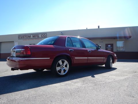 2002 Mercury Grand Marquis - This red 2002 Mercury Grand Marquis sedan is viewed from the rear 3/4 angle in front of a commercial building.