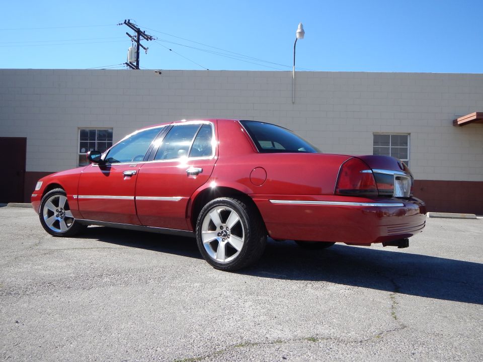 Red 2002 Mercury Grand Marquis parked outside a building, viewed from the rear quarter