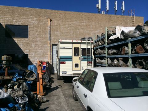 1997 Dodge 3500 - A white motorhome is parked in an industrial area with a white sedan in the foreground.