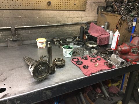 1997 Dodge 3500 - Various transmission gears and components are organized on a workbench, with a container labeled 'Trans' in the background.