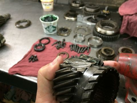 1997 Dodge 3500 - Damaged transmission gears are laid out on a workbench, suggesting a rebuild is underway.