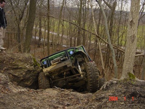 1992 Ford Bronco - Off-road vehicle navigating a steep, muddy trail with large tires.