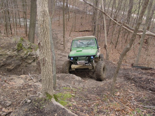 Green off-road vehicle with large tires on a muddy trail