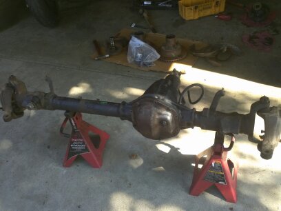 1995 Ford Bronco - Differential axle assembly on jack stands with various automotive parts scattered around.