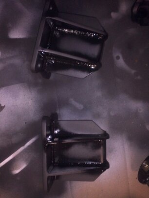1995 Ford Bronco - Two black metal parts, possibly engine mounts, are shown after being painted.