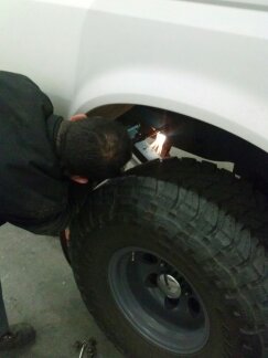 1995 Ford Bronco - Welding work being performed on the wheel well of a white vehicle.