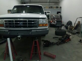 1995 Ford Bronco - A 1995 Ford Bronco is being worked on in a garage, with another vehicle visible in the background.
