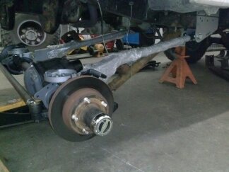 1995 Ford Bronco - Close-up view of a vehicle's front axle and suspension system undergoing maintenance.