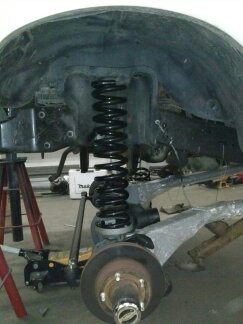 1995 Ford Bronco - Close-up view of a vehicle's front suspension system, including a large coil spring and brake rotor.