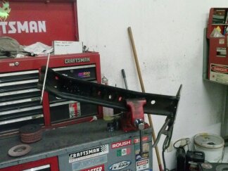 1995 Ford Bronco - A metal component is secured in a vise, ready for work in a garage setting.
