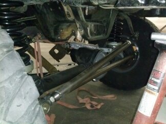 1995 Ford Bronco - Undercarriage view of a vehicle's suspension system, showing the tire and linkage.