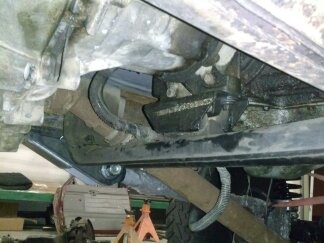 1995 Ford Bronco - Close-up of the underside of a vehicle, showing drivetrain parts and suspension components.