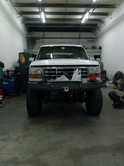 1995 Ford Bronco - Front view of a white Ford Bronco parked inside a garage with tools and equipment visible in the background.