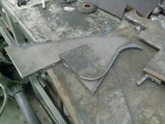 1995 Ford Bronco - Metal parts are laid out on a workbench, possibly for vehicle customization or repair.