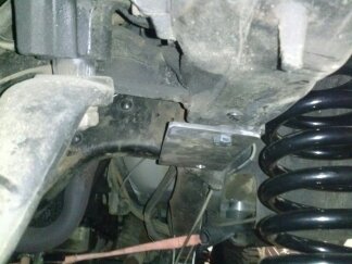 1995 Ford Bronco - Underside view of vehicle suspension system, showing modified components and coil spring.