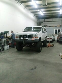 1995 Ford Bronco - A white Ford Bronco is parked inside a garage, with another car visible in the background.