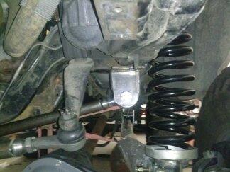 1995 Ford Bronco - Detail of vehicle suspension components, including a coil spring and steering linkage. A Supermotors logo is present in the lower right cor…