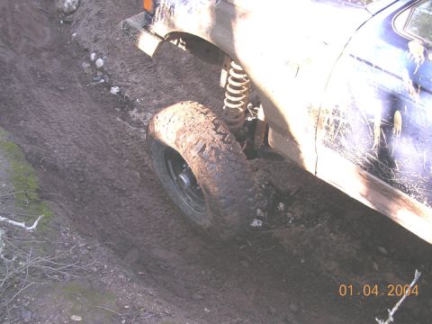 1994 Ford Bronco - Vehicle tire and suspension on a muddy off-road trail.