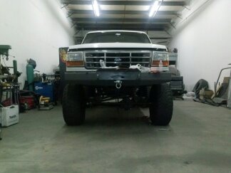 1995 Ford Bronco - Front view of a white Ford Bronco with aftermarket modifications, parked indoors.