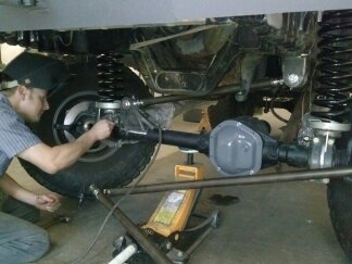 1995 Ford Bronco - Vehicle suspension and axle components are visible as a man performs maintenance.