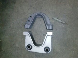 1995 Ford Bronco - Two metal suspension components are laid out on a concrete floor, ready for installation.