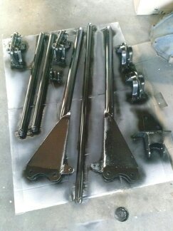 1995 Ford Bronco - Several black painted suspension parts are arranged on a drop cloth, ready for installation.