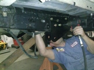 1995 Ford Bronco - Mechanic works on the undercarriage of a vehicle. The SuperMotors.net logo is visible in the lower right corner.