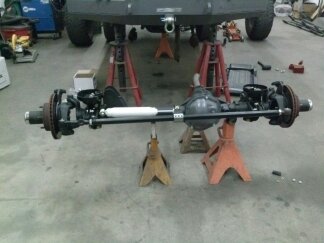 1995 Ford Bronco - A vehicle's rear axle assembly is shown supported by jack stands in a workshop setting.