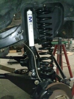 1995 Ford Bronco - Close-up of a vehicle's front suspension system, a coil spring and a white shock absorber with visible branding.