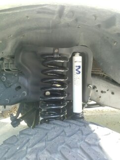 1995 Ford Bronco - A close-up view shows a suspension coil spring and a white shock absorber with blue markings.
