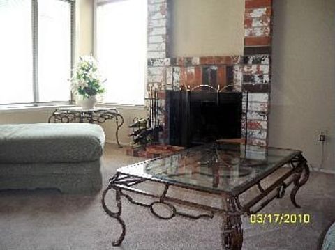 1989 Ford Bronco - Interior view of a living room a brick fireplace, a large ottoman, and a glass-top coffee table.