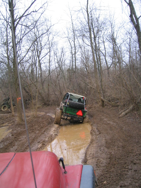 1992 Ford Bronco - Off-roading adventure on a muddy trail with multiple vehicles traversing the difficult terrain.