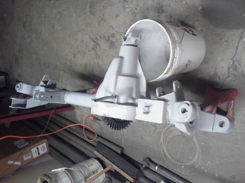 1968 Ford Bronco - A vehicle's front axle assembly, recently painted and ready for installation, sits on a workshop floor.