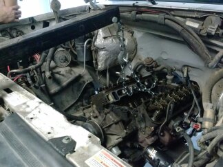 1995 Ford Bronco - Engine bay work in progress, with a chain hoist attached to the engine for removal or installation.