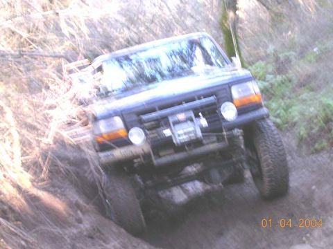 1994 Ford Bronco - This 1994 Ford Bronco is shown navigating a steep, muddy trail with trees in the background.