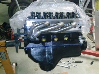 1995 Ford Bronco - Ford V8 engine assembly with chrome headers and aluminum heads, partially covered.