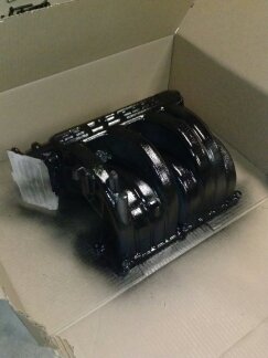 1995 Ford Bronco - A black intake manifold sits in a cardboard box, with the SuperMotors logo visible below.