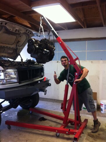 1995 Ford Bronco - Engine removal in progress on a gray truck, with a man supervising the operation.