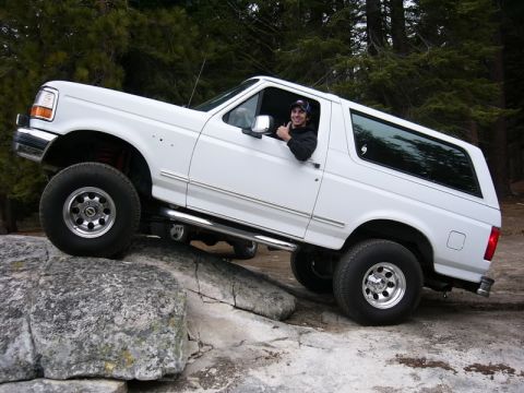 1995 Ford Bronco - A white 1992 Ford Bronco navigates a rocky trail with a driver giving a thumbs-up.