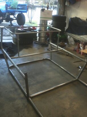1995 Ford Bronco - A custom-built roll cage is shown in a garage setting, with a blue truck visible in the background.