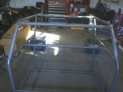 1995 Ford Bronco - A metal roll cage frame sits in a garage, supported by milk crates.
