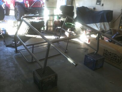 1995 Ford Bronco - A metal roll cage frame is shown in a garage, with a red Jeep visible in the background.