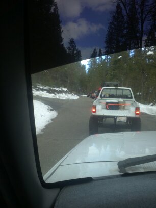 1995 Ford Bronco - A white pickup truck is driving on a road with snow on the sides, with other vehicles ahead.
