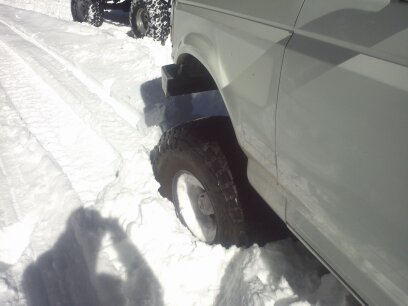 1995 Ford Bronco - A white SUV is partially submerged in snow, with another vehicle visible in the background.